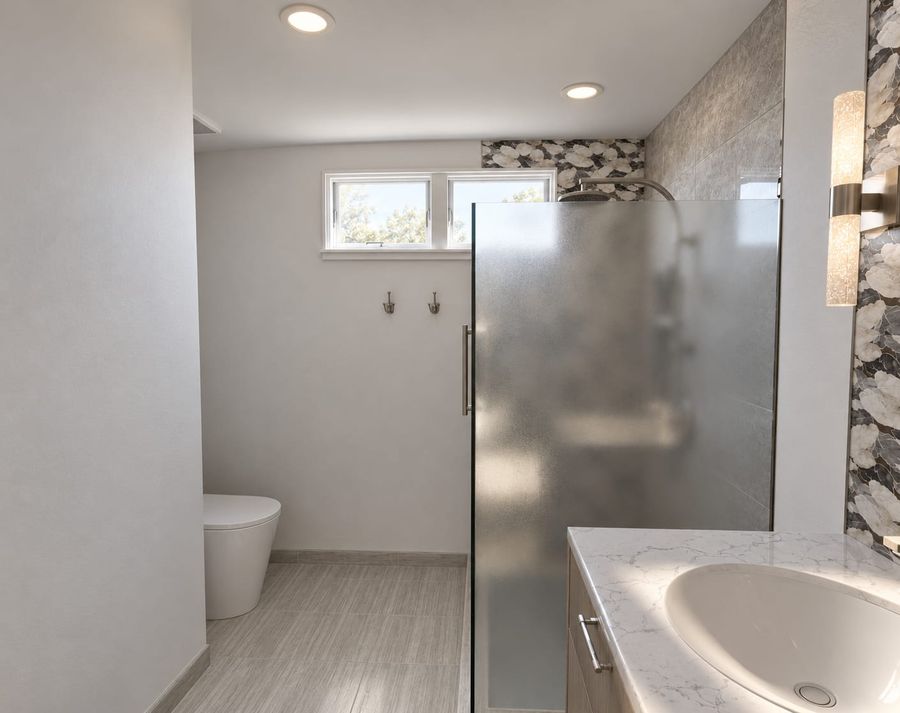 3D rendering of the same bathroom showing the frosted shower panel, a wall-hung toilet beneath a high window, brushed nickel hooks, and the marble-look vanity top