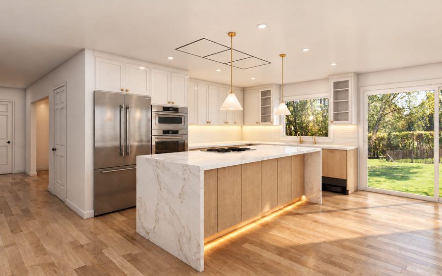 3D rendering of the same kitchen from an angle: marble waterfall island with cooktop, light oak lower cabinets, stainless refrigerator and wall ovens, brass pendants, and a large sliding door to the yard